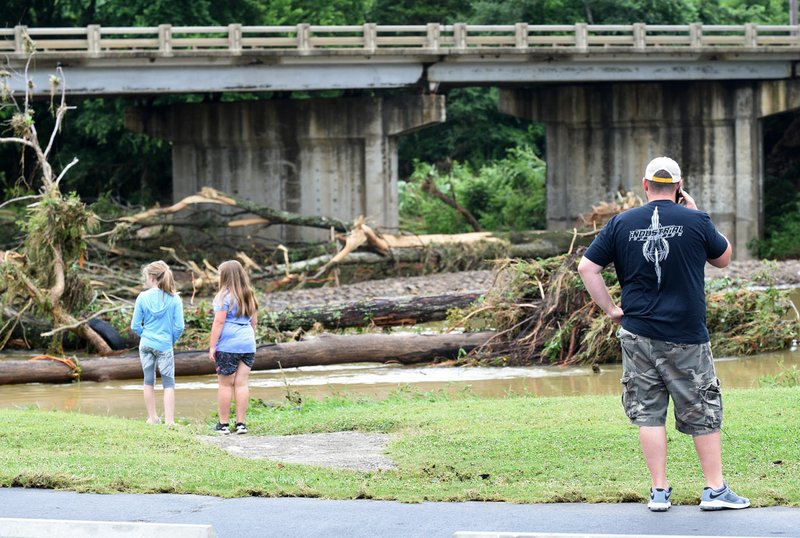 NWA Democrat-Gazette/DAVID GOTTSCHALK Washington County residents look Monday at debris washed into Riverside Park from the West Fork of the White River in West Fork. Heavy rain caused flooding in areas of Northwest Arkansas over the weekend.