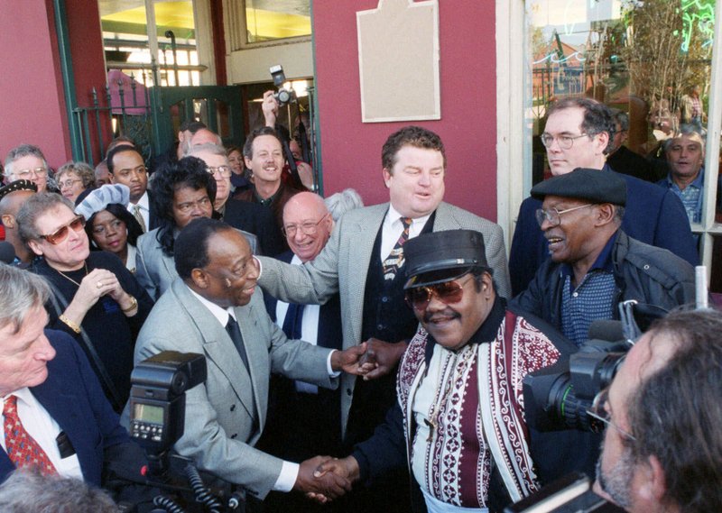 CORRECTS THAT BARTHOLOMEW IS AT LEFT, NOT RIGHT. - FILE - In a Dec. 10, 1999 file photo, Fats Domino, center right, shakes hands with Dave Bartholomew, left, amid a crowd of former colleagues at the 50th anniversary observance of Domino's first recording session in New Orleans. Bartholomew, a giant of New Orleans music and a rock n' roll pioneer who with Fats Domino co-wrote and produced such classics as &quot;Ain't That a Shame,&quot; ''I'm Walkin'&quot; and &quot;Let the Four Winds Blow,&quot; died Sunday, June 23, 2019 in a hospital in a New Orleans suburb, his eldest son Dave Bartholomew Jr. told The Associated Press. He was 100 years old. (Jennifer Zdon/The Times-Picayune via AP, File)