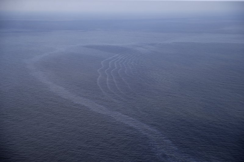 FILE - This March 31, 2015, aerial file photo, shows an oil sheen drifting from the site of the former Taylor Energy oil rig in the Gulf of Mexico, off the coast of Louisiana. A new federally led estimate of oil seeping from a platform toppled off Louisiana 14&#xbd; years ago is below other recent estimates. But the report contradicts the well owner&#x2019;s assertions about the amount and source of oil. Oil and gas have been leaking into the Gulf of Mexico since a subsea mudslide caused by Hurricane Ivan on Sept. 15, 2004 knocked over a Taylor Energy Co. production platform. (AP Photo/Gerald Herbert, File)