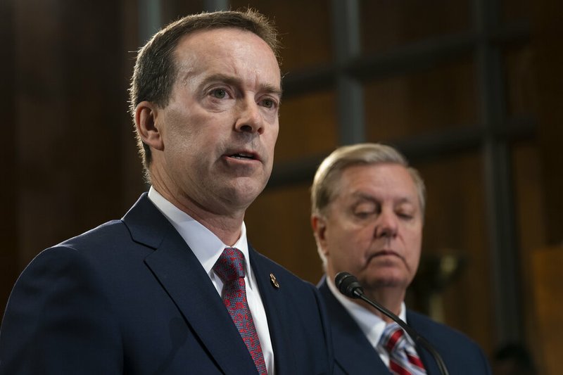 FILE - In this May 15, 2019, file photo, acting U.S. Customs and Border Protection Commissioner John Sanders, left, joins Senate Judiciary Committee Chairman Lindsey Graham, R-S.C., right, on Capitol Hill in Washington. Sanders says he's stepping down amid outrage over his agency's treatment of detained migrant children and said in a message to CBP employees Tuesday that he would resign on July 5. (AP Photo/J. Scott Applewhite)