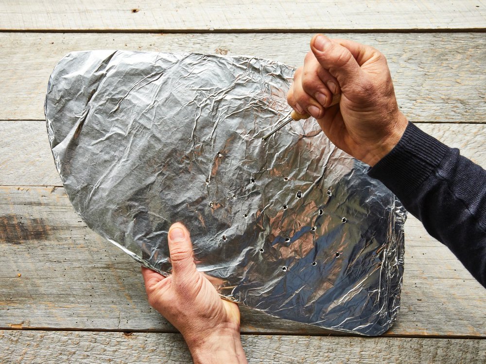 Create a platform for cooking the brisket by cutting a flat piece of cardboard the size and shape of the brisket. Cover the cut cardboard with foil and using an ice pick or a metal skewer, poke holes in it at 1-inch intervals. Photo by Tara Donne (The New York Times)