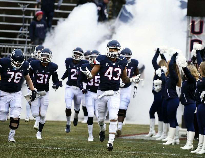 Connecticut linebacker Darrian Beavers (43) leads his team onto the field before a 2018 game against Temple. With Connecticut expected to accept an invitation to return to the Big East in every sport, except football, the Huskies are expected to compete as an independent when they leave the American Athletic Conference.