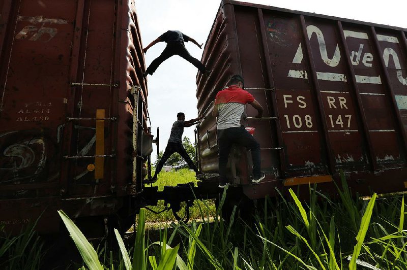 Migrants hop on a northbound freight train Tuesday in Salto del Agua in Mexico’s Chiapas state. 