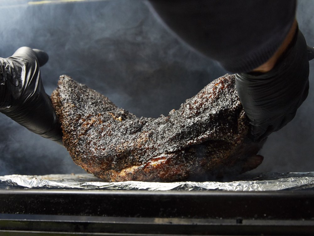 Barbecued brisket goes under the bend test to check its doneness: lift the meat by the ends, if it sags in the middle, it's done. Photo by Tara Donne (The New York Times)