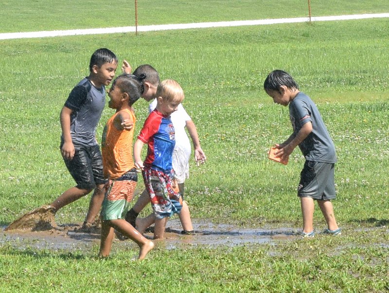 Westside Eagle Observer/MIKE ECKELS &quot;Sometimes the simplest things in life are the ones that give us the greatest pleasure&quot; is something these Sparks Summer School students learned while playing in a mud puddle created by the Decatur Fire Department during Water Day at Northside Elementary June 20.