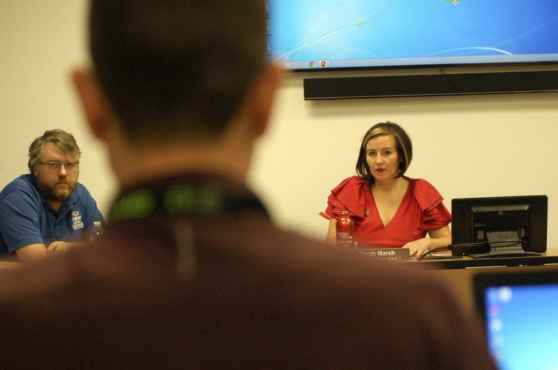 NWA Democrat-Gazette/STACY RYBURN Sloan Scroggin (left) and Sarah Marsh (right), both Fayetteville City Council members, listen Tuesday as Peter Nierengarten (center), the city's sustainability director, speaks during the council's meeting at City Hall. The council went over a proposal to regular electric scooter rideshare programs in the city.