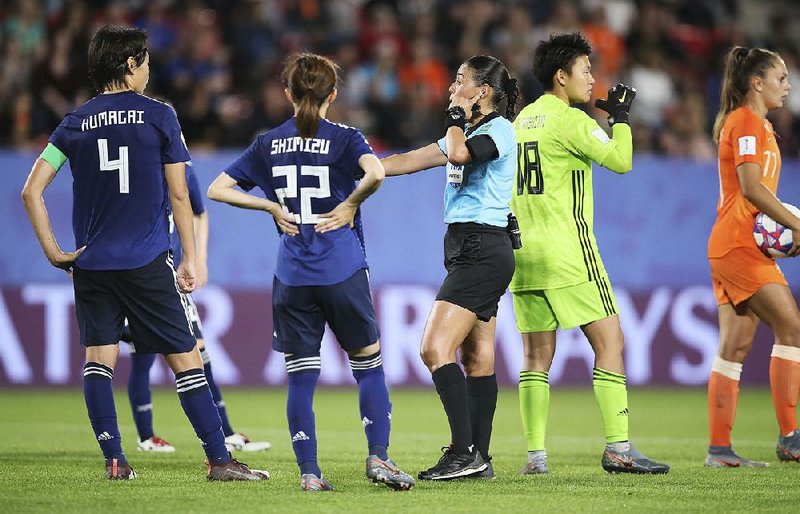 Referee Melissa Borjas (center) consults with Video Assistant Referee after awarding a penalty to the Netherlands team during a round of 16 match against Japan on Tuesday. Lieke Martens scored after the review, and the Dutch won the match 2-1. 