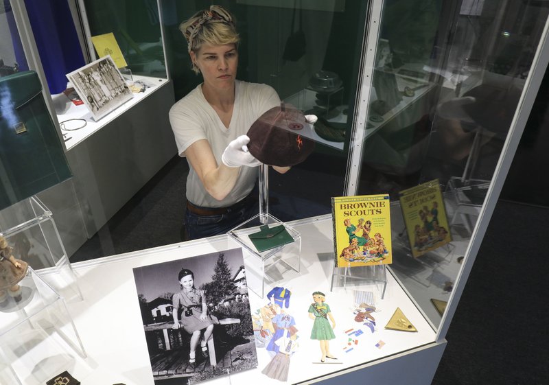 Emily Hadland adjusts pieces in the Esse Purse Museum exhibit "Purses with Purpose: Girl Scouts Through the Decades." The exhibit is just one in central Arkansas that may appeal to young visitors. Arkansas Democrat-Gazette/Staton Breidenthal