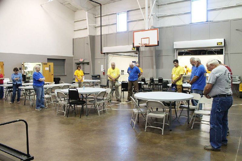Disaster relief volunteers from Arkansas and Tennessee bow their heads in prayer before dining together in the Family Life Center of Central Baptist Church in Conway on Monday. Individuals in the group of Southern Baptists will work for a week at a time; and Dan West, leader of the unit in Conway, said the group has been stationed at Central Baptist for two weeks and will remain so for a length of time determined by community need.