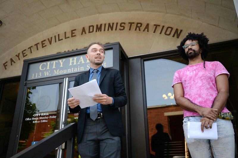 NWA Democrat-Gazette/ANDY SHUPE Stephen Coger (left), director and founder of the Arkansas Justice Collective, speaks Thursday on the steps of City Hall with Cory Perry after the group studied marijuana-related arrests in Fayetteville over several years. A 2008 vote made city policy on misdemeanor marijuana arrests a low priority.