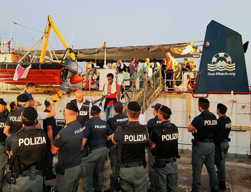Migrants disembark from the Dutch-flagged Sea-Watch 3 ship, at Lampedusa island's harbor, Italy, Saturday, June 29, 2019. Forty migrants have disembarked on a tiny Italian island after the captain of the German aid ship which rescued them docked without permission. Sea-Watch 3 rammed an Italian border police motorboat as it steered toward the pier on Lampedusa. 