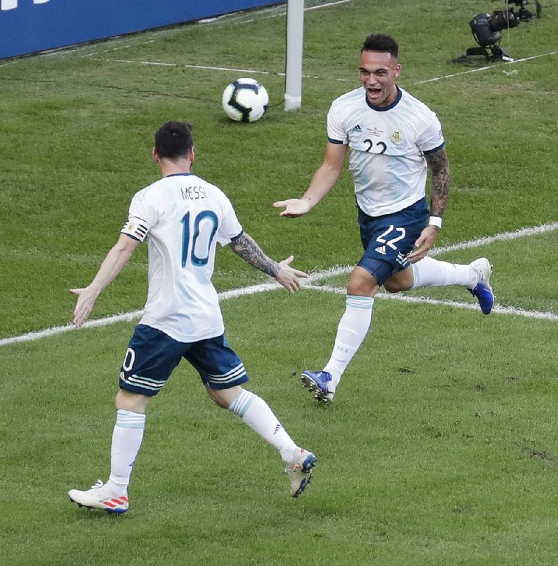 Argentina’s Lautaro Martinez (right) celebrates scoring his side’s opening goal with teammate Lionel Messi during a Copa America quarterfinal Friday at the Maracana stadium in Rio de Janeiro, Brazil. None of Argentina’s three starting strikers — Martinez, Messi and Sergio Aguero — can fill defensive gaps in the midfield, causing a dilemma for Coach Lionel Scaloni as he figures out his game plan for Tuesday’s semifinal against Brazil.