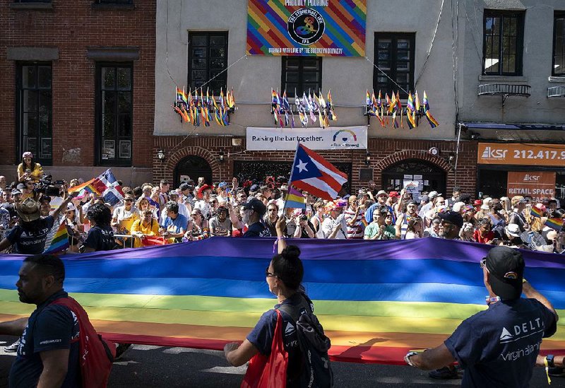A group marching in New York’s pride parade carries a rainbow banner Sunday as it passes the Stonewall Inn, the site of a 1969 police raid that sparked the gay-rights movement. 