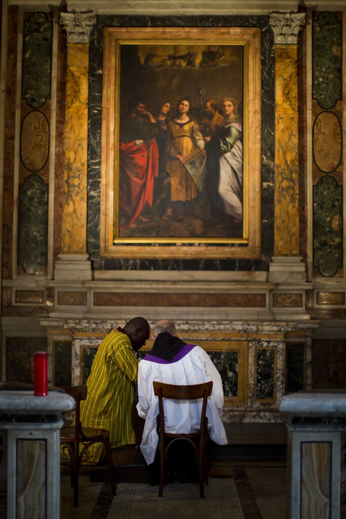 FILE - In this April 26, 2014 file photo, a Roman catholic priest, back to camera, listens to a man's confession during a mass for late Pope John Paul II and John XXIII in Saint Luigi dei Francesi (St. Louis of the French) church, in Rome. The Holy See's Apostolic Penitentiaria, a tribunal which deals with absolution and confessional matters, reiterated the secrecy obligation in a six-page document made public Monday, July 1, 2019, by the Vatican. (AP Photo/Emilio Morenatti, file)