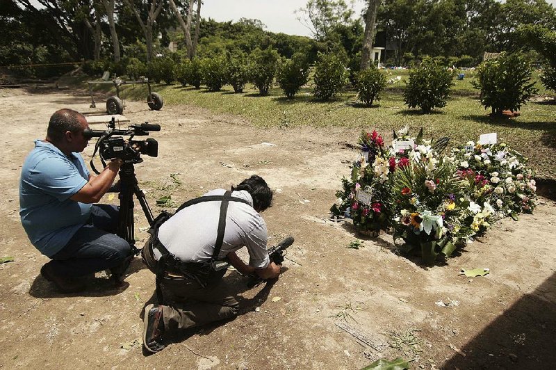 Members of the media take photos of the grave of Oscar Alberto Martinez Ramirez and his 23-month-old daughter, Angie Valeria, after their burial Monday at a cemetery in San Salvador, El Salvador.