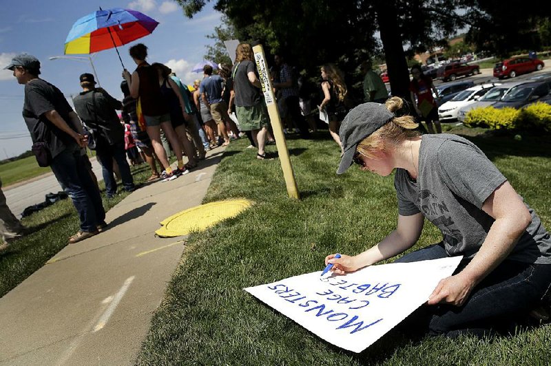 Julie Steinbach of Mission, Kan., makes a sign Tuesday outside the Overland Park, Kan., office of Republican U.S. Sen. Pat Roberts during a protest about conditions of immigration detention centers. 