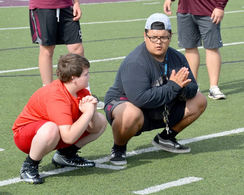Graham Thomas/Herald-Leader Siloam Springs football player Marco Salcedo, right, demonstrates a stretching drill to a Panther Academy participant on June 11 at Panther Stadium.