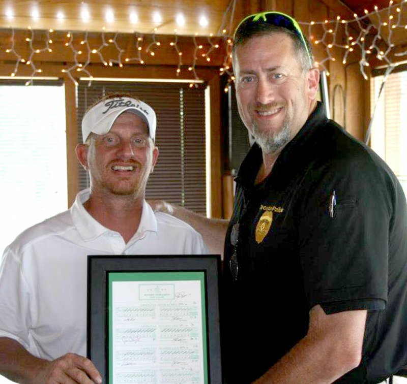 Westside Eagle Observer/SUBMITTED Decatur Police Officer Steve Grizzle (right) presents Brad Elam with an autographed Jack Nickolas scorecard he won during the silent auction portion of the Decatur Police Department fundraiser golf tournament June 8 at The Creeks Golf Course in Cave Springs. Elam, an employee of Simmons in Decatur, placed the highest bid on the scorecard signed by the golf legend.