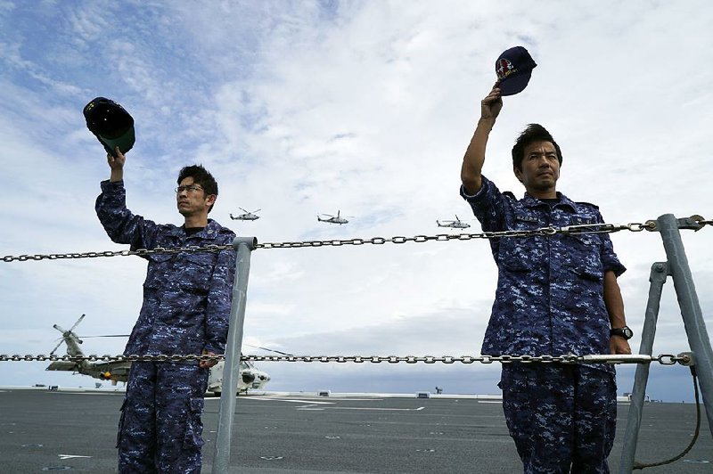 Crew members of the Japanese helicopter carrier Izumo join in a farewell pass June 28 with the Philippines navy ship Davao del Sur at the end of joint exercises in the Sulu Sea. 