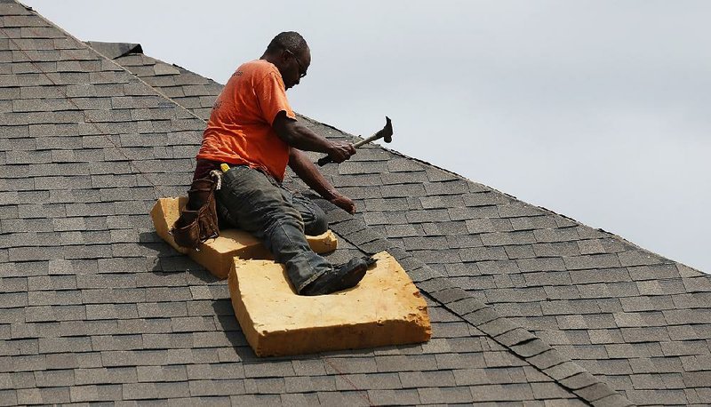 A worker balances on a steep roof last month as he shingles a new house in Brandon, Miss. U.S. companies added 102,000 Jobs in June, less than forecast. 