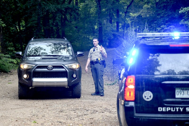 A Benton County Sheriff's Deputy directs traffic, Friday, July 5, on the intersection of Crossover Road and Gordon Hollow Road in Gravette. Police responded to a shooting situation that left four people dead in an apparent murder-suicide on a nearby property. All four people are related or lived at the residence. One body was found on the driveway. Authorities do not believe there is a danger to the public.