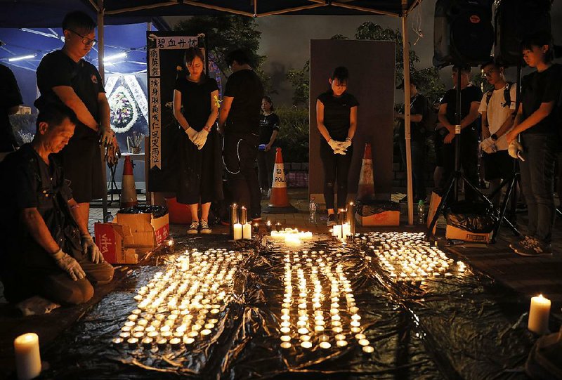 People pray during a minute of silence at Saturday night’s vigil in Hong Kong. 