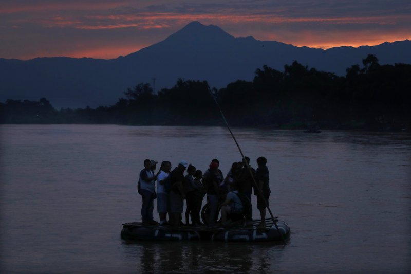 FILE - In this early Monday, June 10, 2019 file photo, Central American migrants stand on a raft to cross the Suchiate River from Guatemala to Mexico, with the Tacana volcano in the background, near Ciudad Hidalgo, Mexico. A record 71 million people were forcibly displaced around the world in 2018, according to a report last month by the United Nations refugee agency, in places as diverse as Turkey, Uganda, Bangladesh and Peru. (AP Photo/Marco Ugarte)