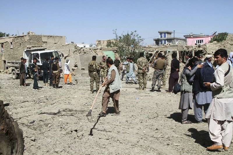 Afghan security personnel inspect the site of Sunday’s car bomb attack in Ghazni province. 