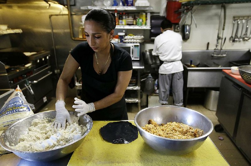 Mariana Moncada, who came to the U.S. from Honduras, prepares food last month in a kitchen in Chelsea, Mass. 