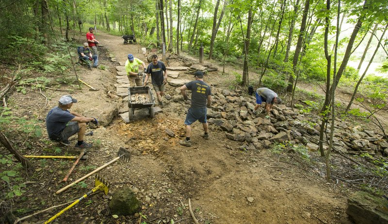 NWA Democrat-Gazette/BEN GOFF &#8226; @NWABENGOFF Volunteers with Ozarks Off Road Cyclists add rock armoring Saturday at the intersection of Last Call and Terrapin Station at Kessler Mountain Regional Park in Fayetteville. Volunteers used 11 tons of stone to shore up the often muddy and erosion-damaged section of the trail and recently completed similar projects on other trails at the park. The Ozark Off Road Cyclists, the local chapter of the International Mountain Bicycling Association, are raising money through their Kessler Campaign to pay for further improvements and future trails at the park.