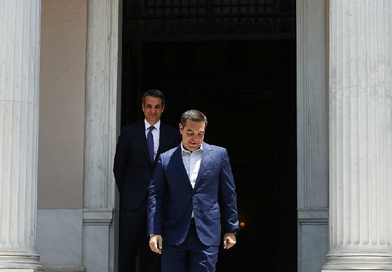 Newly elected Prime Minister Kyriakos Mitsotakis (background) watches Monday as predecessor Alexis Tsipras leaves the Maximos Mansion in Athens, Greece.