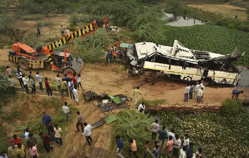 A crane pulls the damaged bus from a drain Monday after it crashed near Agra, India.