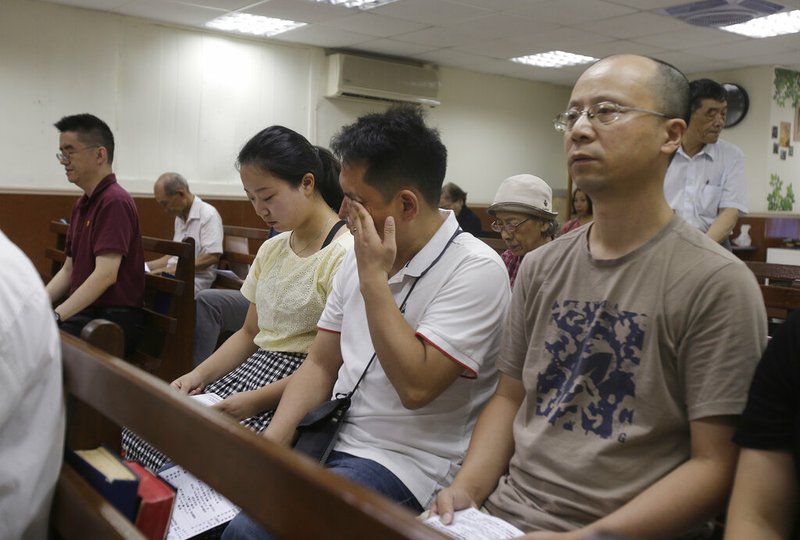 In this Sunday, July 7, 2019, photo, from right; Liao Qiang, Peng Ran and Ren Ruiting pray in silence during service at a church in Taipei, Taiwan. After fleeing to Taiwan from China last week, Liao Qiang worshipped publicly Sunday for the first time since Chinese authorities shut down his church in December. Liao and his daughter described living under surveillance for the past seven months after authorities detained them and other members of their church. (AP Photo/Chiang Ying-ying)
