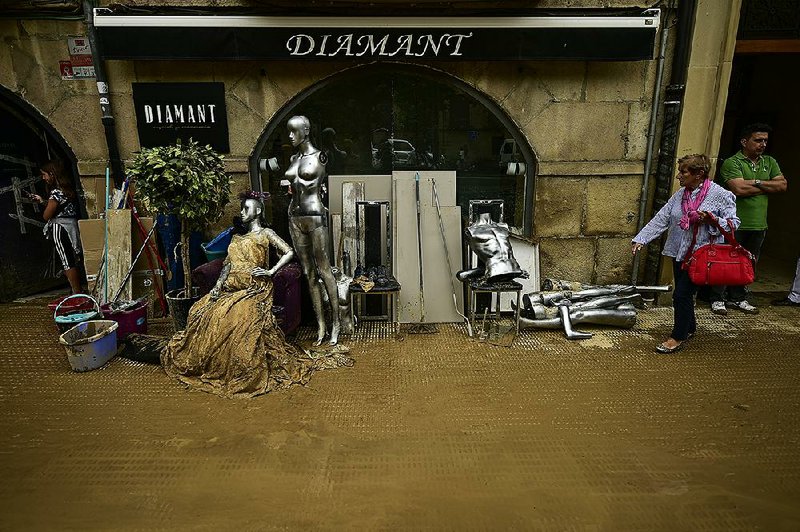 A pedestrian on Tuesday passes a shop damaged by the heavy rainfall in Tafalla, Spain. 