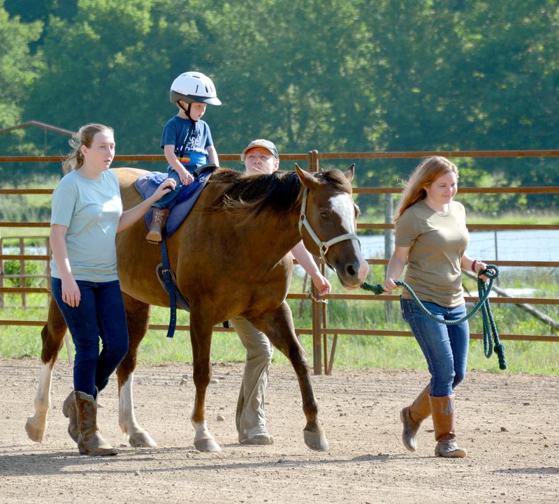 Janelle Jessen/Herald-Leader Zander Thompson (second from left) receives speech therapy from Holly Meyers (second from right) as side-walker Sarah Ragsdale (left) and horse-handler LeTausha Ahrents (right) help with the therapy session.