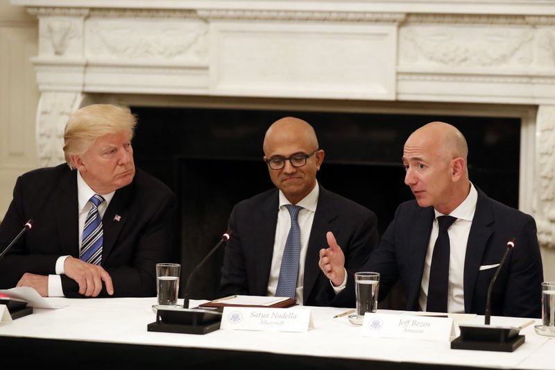 FILE - In this June 19, 2017, file photo President Donald Trump, left, and Satya Nadella, Chief Executive Officer of Microsoft, center, listen as Jeff Bezos, Chief Executive Officer of Amazon, speaks during an American Technology Council roundtable in the State Dinning Room of the White House in Washington. Amazon and Microsoft are battling for a $10 billion opportunity to build the U.S. military its first "war cloud." (AP Photo/Alex Brandon, File)