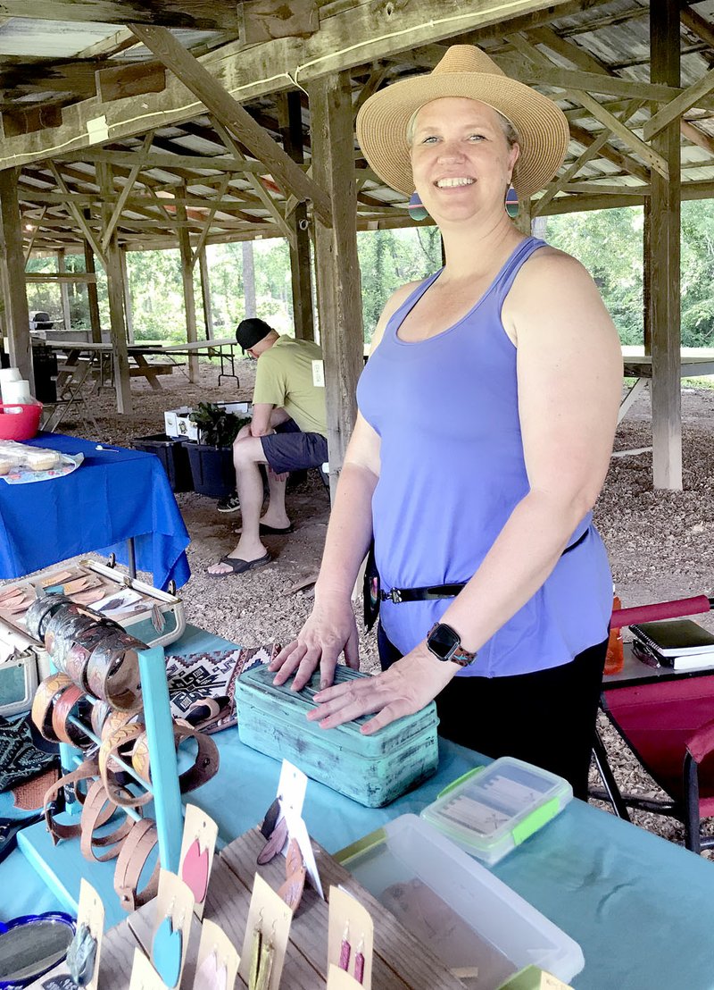 Sally Carroll/McDonald County Press Lisa Florey shows off her leather items that she has created. Florey started designing and working with leather, designing bags and jewelry, after she needed a bag to use while trail riding on her horse. Her company is expanding and Florey has enjoyed a great deal of success. She shows and sells her items at the Powell and Pineville Farmers Markets.