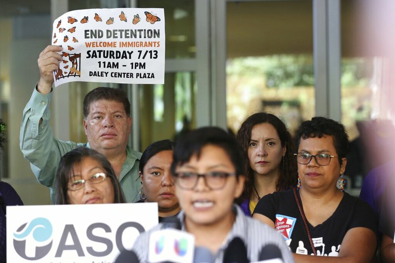 Demonstrators hold placards as Rey Wences, organizer at Organized Communities Against Deportations (OCAD) addresses reporters during a new conference outside the U.S. Citizenship and Immigration Services offices in Chicago, Thursday, July 11, 2019. A nationwide immigration enforcement operation targeting people who are in the United States illegally is expected to begin this weekend. (AP Photo/Amr Alfiky)