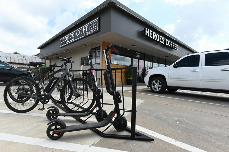 NWA Democrat-Gazette/SPENCER TIREY Goat Scooters, scooters that are rented by scanning a QR code, are seen on a bike rack outside Heros Coffee and Roastery shop on 8th and A street, Wednesday July 10, 2019 in Bentonville.