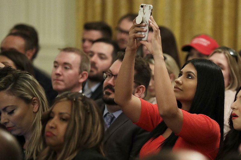 An invited guest gets a photo Thursday as President Donald Trump speaks at a White House “social media summit.” 