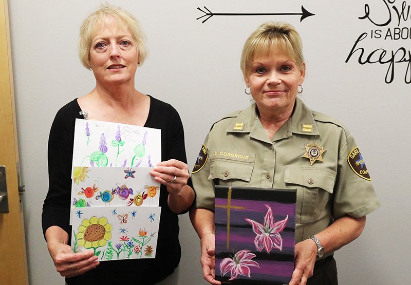 The Sentinel-Record/Richard Rasmussen CREATIVE SPACE: Volunteer Ann Wilson, left, and Capt. Belinda Cosgrove display student artwork created in an art class by inmates at the Garland County Detention Center. The six-week classes are open to 10 students each week and give a creative outlet for inmates to express themselves in a positive way.