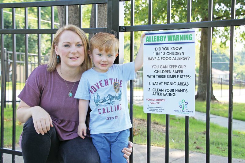 Taylor Parsons and her son, Jackson, 2, stand next to an allergy warning sign posted at Tyndall Park in Benton. Parsons asked the park to post the signs in an effort to bring awareness to children with allergies. 