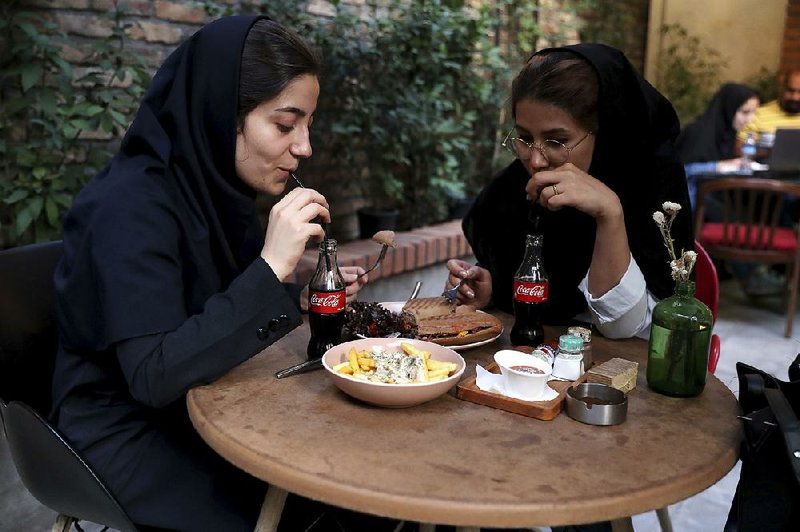 Two Iranians sip Coca-Cola at a downtown Tehran cafe. Products like Coke and Tabasco are still finding their way to Iran despite tensions and sanctions.