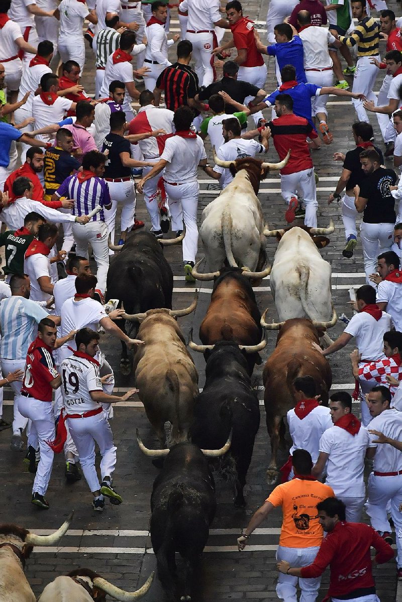 Revelers along with bulls dash through the streets Friday at the San Fermin festival in Pamplona, Spain. 