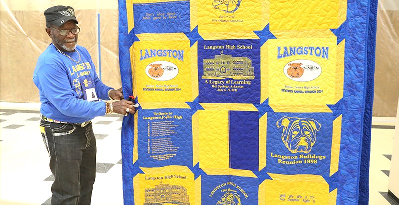 The Sentinel-Record/Richard Rasmussen BLUE AND GOLD: James Ford, Class of 1963, hangs a quilt made of reunion T-shirts up during the Langston Alumni Reunion picnic at Hot Springs World Class High School on Thursday.