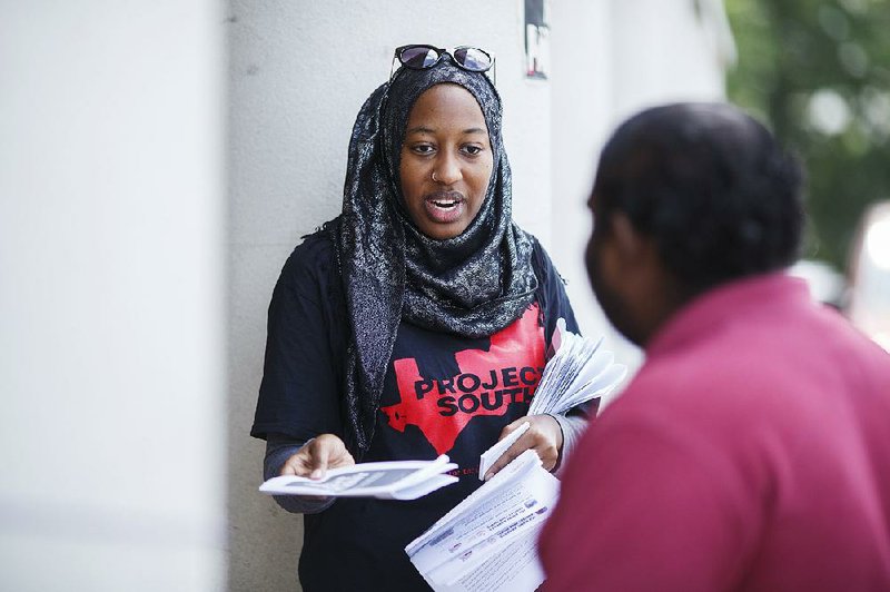 Nicole Fauster, an intern with the nonprofit Project South organization, hands out civil-rights information Saturday in Decatur, Ga., ahead of the immigration raids planned for today.