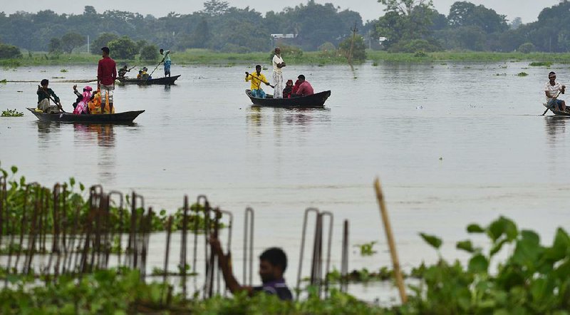 People cross the floodwaters Friday in Ashighar village in India’s Assam state, where officials said the homes of about 900,000 people have been submerged.