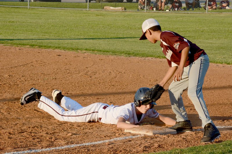 Graham Thomas/Siloam Sunday Siloam Springs shortstop Alec Pearson dives back to first base during a pick off attempt as Littlefield (Texas) first baseman Markus Rosales applies the tag. Littlefield defeated Siloam Springs 10-3 in the opening round of the Cal Ripken Southwest Regional 12-year-old 70 Major Tournament at James Butts Baseball Park in Siloam Springs.