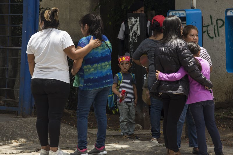 A boy dressed as a clown watches as the Martinez de Leon family console themselves as they mourn the murder of Carlos Alberto Martinez in Guatemala City, Friday, July 12, 2019. Rates of crime in Guatemala are very high. An average of 101 murders per week were reported in 2016, making the country's violent crime rate one of the highest in Latin America. (AP Photo/Oliver de Ros)