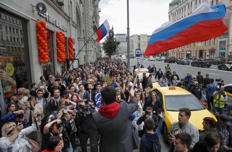 Russian opposition candidate Russian and activist Ilya Yashin, center back to a camera, waves a Russian flag during a protest in Moscow, Russia, Sunday, July 14, 2019. Opposition candidates who run for seats in the city legislature in September's elections have complained that authorities try to bar them from the race by questioning the validity of signatures of city residents they must collect in order to qualify for the race. (AP Photo/Pavel Golovkin)